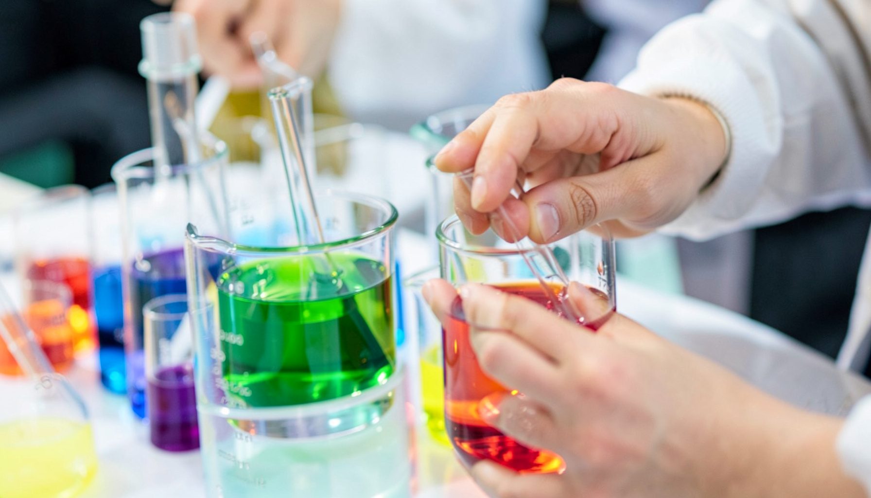 Close-up of hands-on science experiment with colorful liquids in beakers